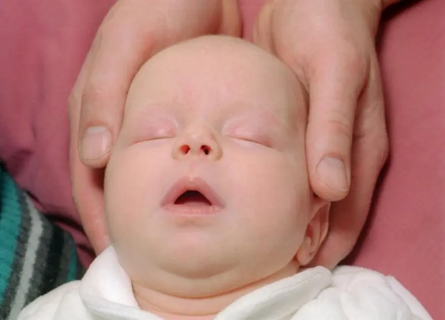 A person holding the head of a newly born baby